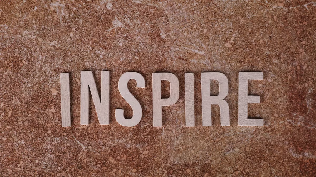 Inspirational word 'INSPIRE' on a textured stone background for motivation.